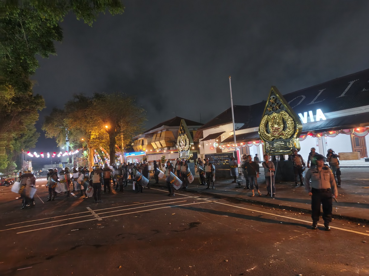 Anggota mencoba memukul mundur massa demonstran usai ricuh di depan Mako Polres Magelang Kota, Jumat (29/8/2025) malam.