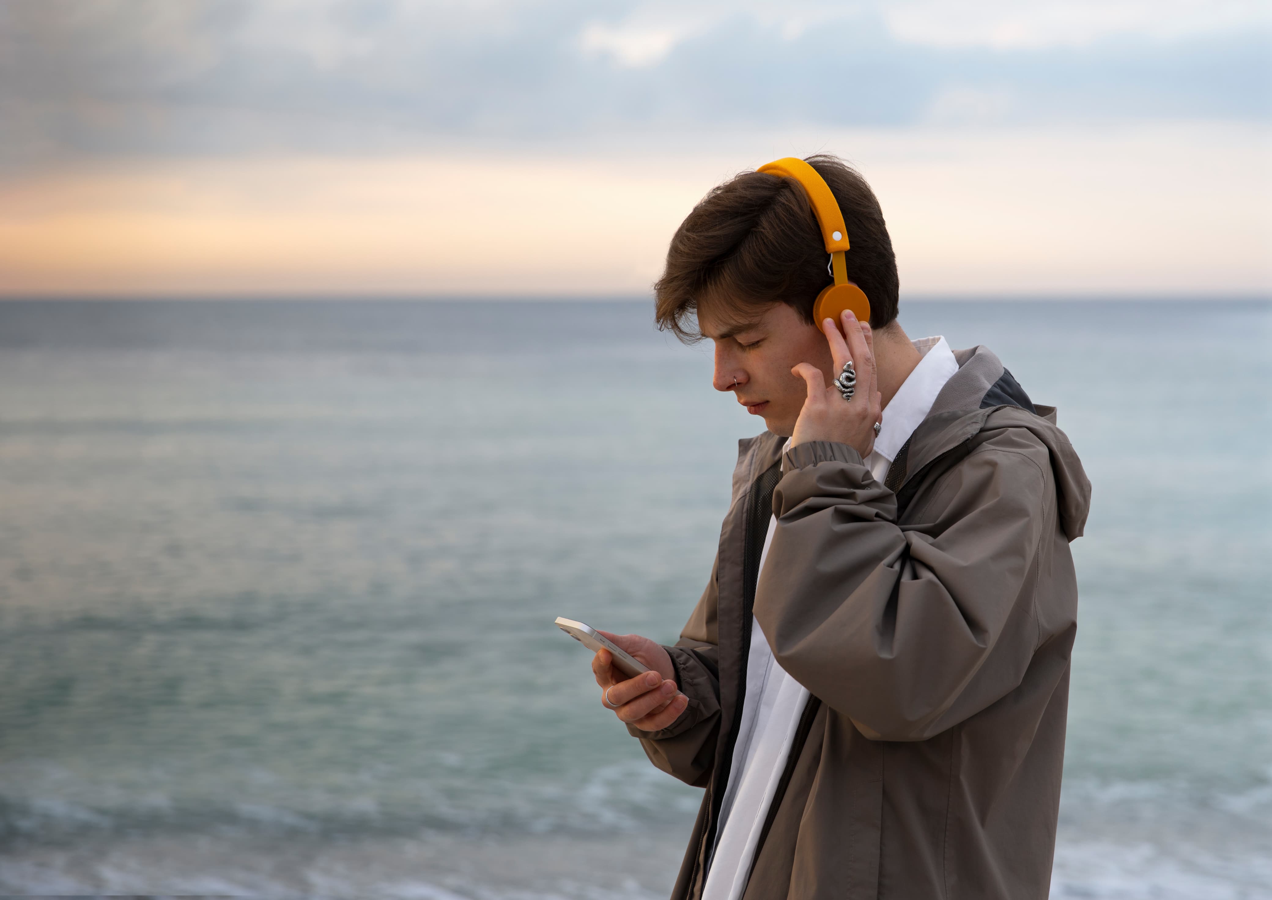 Seorang pria mendengarkan lagu dengan background di tepi pantai