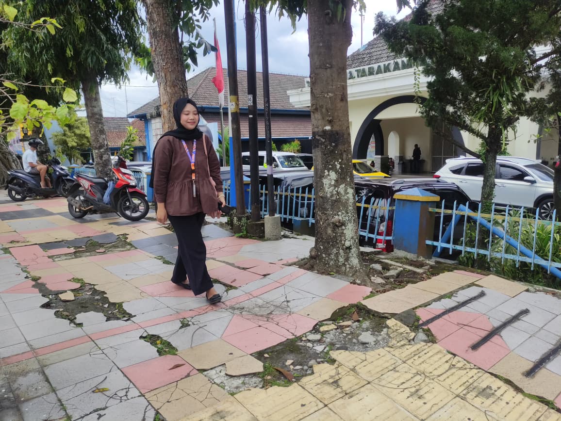 Seorang pejalan kaki melintasi trotoar yang retak dan berlubang di pusat Kota Magelang. Warga mendesak perbaikan segera demi keselamatan.