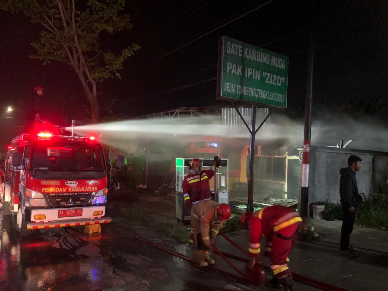 Petugas Damkar Temanggung menyemprotkan air ke warung sate yang terbakar pada Rabu (8/10/2025) malam.