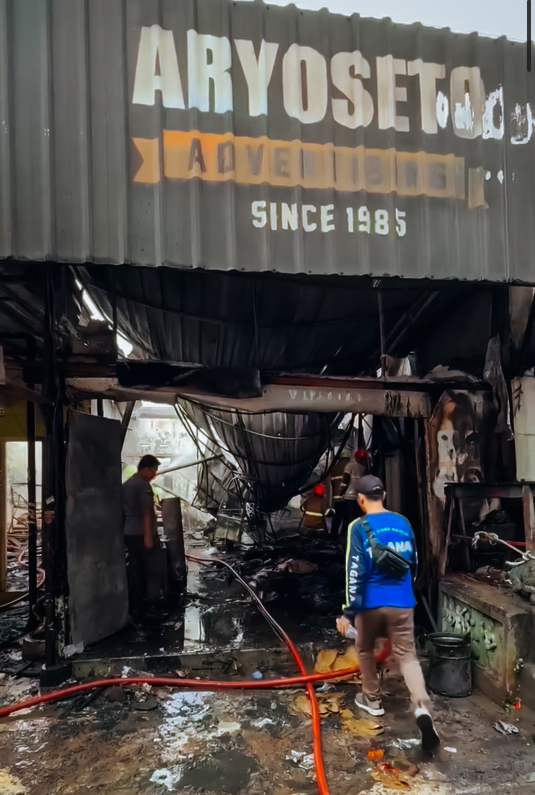 Petugas pemadam kebakaran bersama warga bergotong royong memadamkan api yang melalap bangunan Percetakan Aryoseto Advertising di Jalan Ikhlas, Magersari, Kota Magelang, Minggu pagi (12/10/2025).