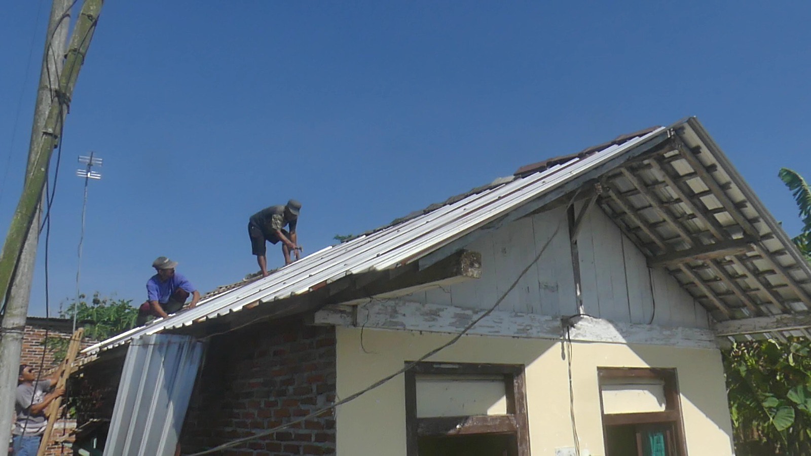 Warga Kelurahan Manding, Temanggung tengah memperbaiki rumah  yang tersapu angin kencang pada Senin petang (13/10/2025).