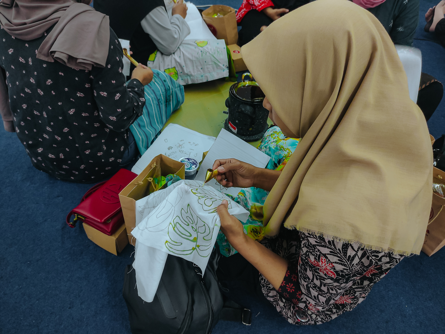 Seorang peserta dengan tekun mencanting kain bermotif daun saat kegiatan Nyanting Batik di Basement Trio Plaza Magelang, Sabtu (18/10/2025)