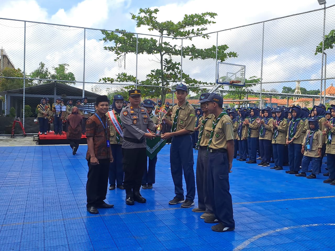 Kapolsek Bandongan AKP Prapta Susila menyerahkan piala pada siswa yang berprestasi dalam upacara di halaman SMK Muhammadiyah 1 Bandongan, Jumat (17/10/2025).