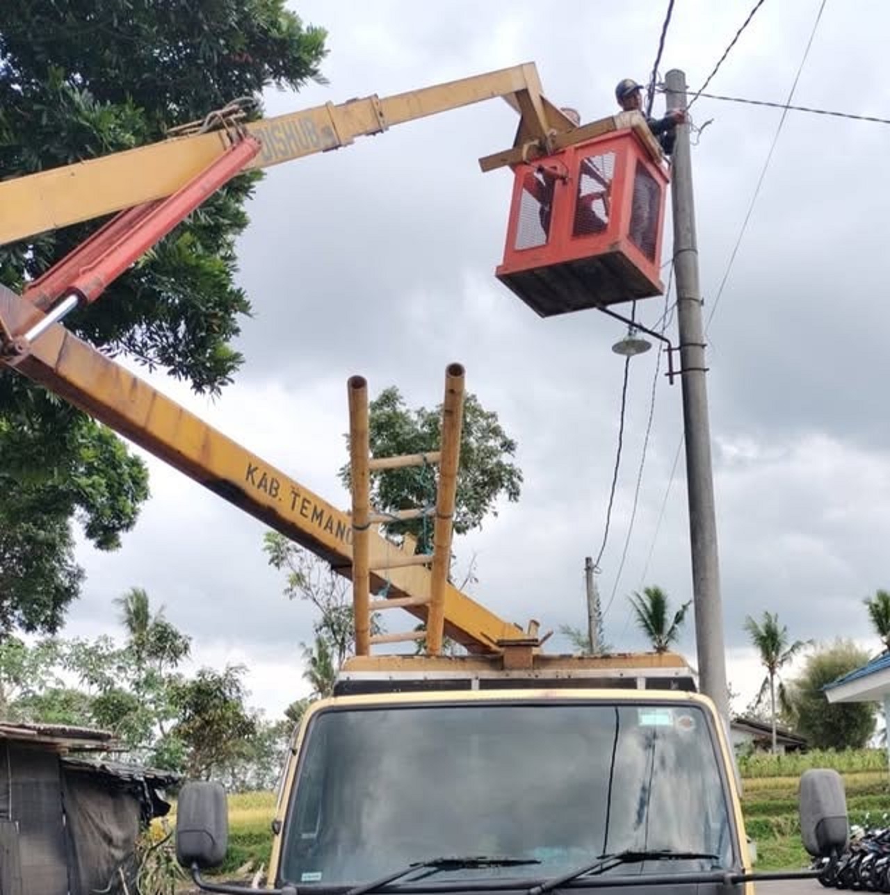Petugas Dishub Temanggung  tengah memperbaiki lampu penerangan jalan umum.