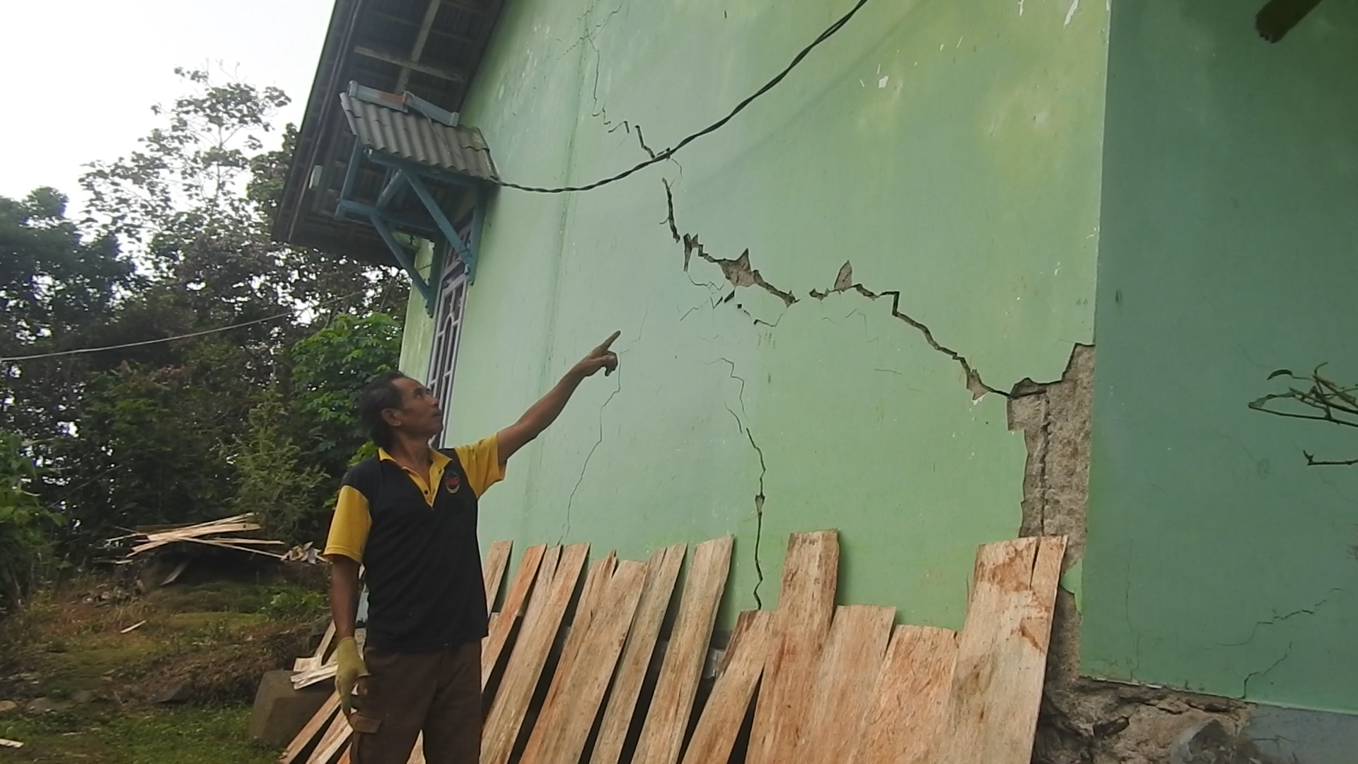 Warga Desa Pucungkerep menunjukkan tembok rumahnya yang rejak memanjang.
