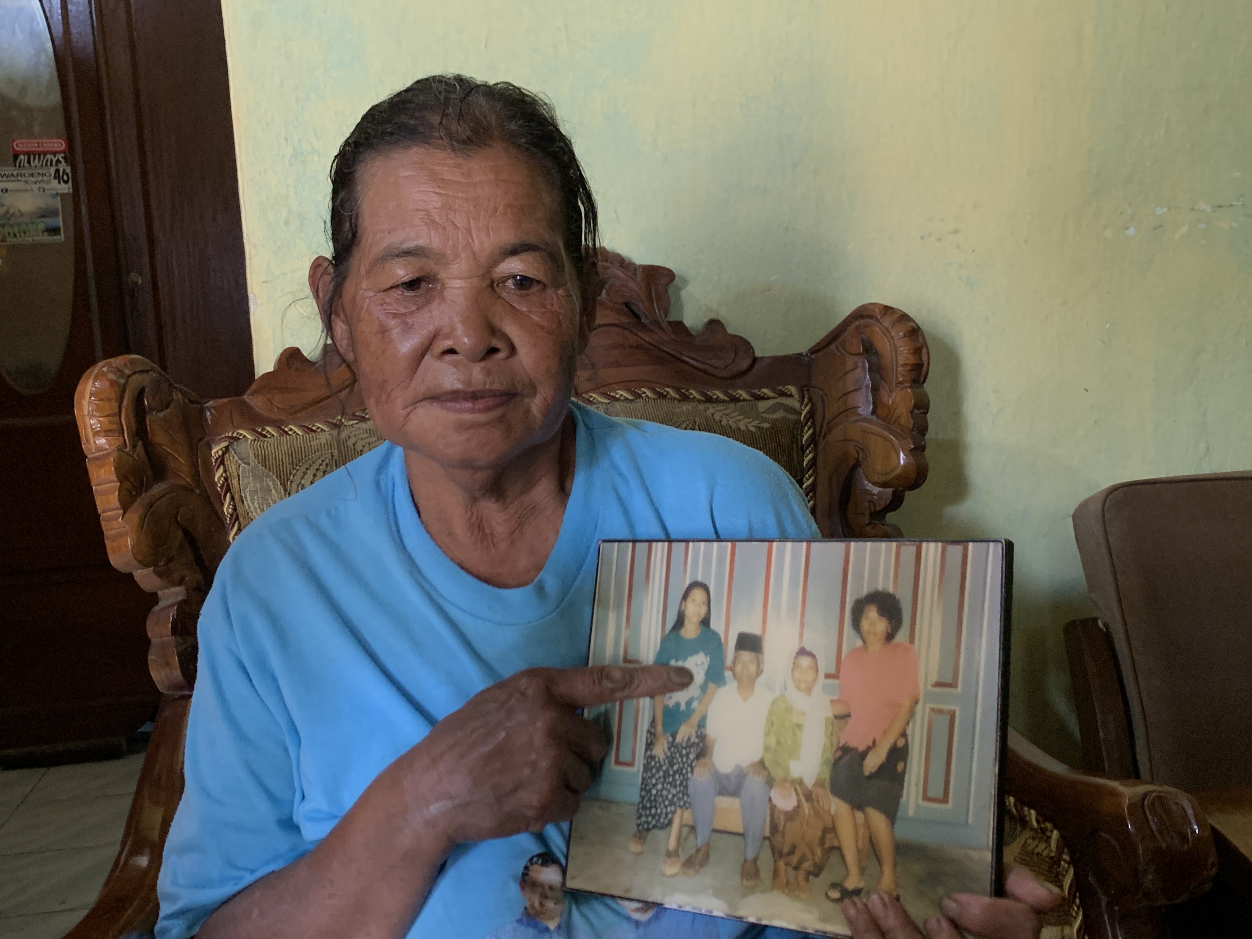 Walmi, kakak ipar Seni menunjukkan foto Seni (baju hijau) dalam foto.