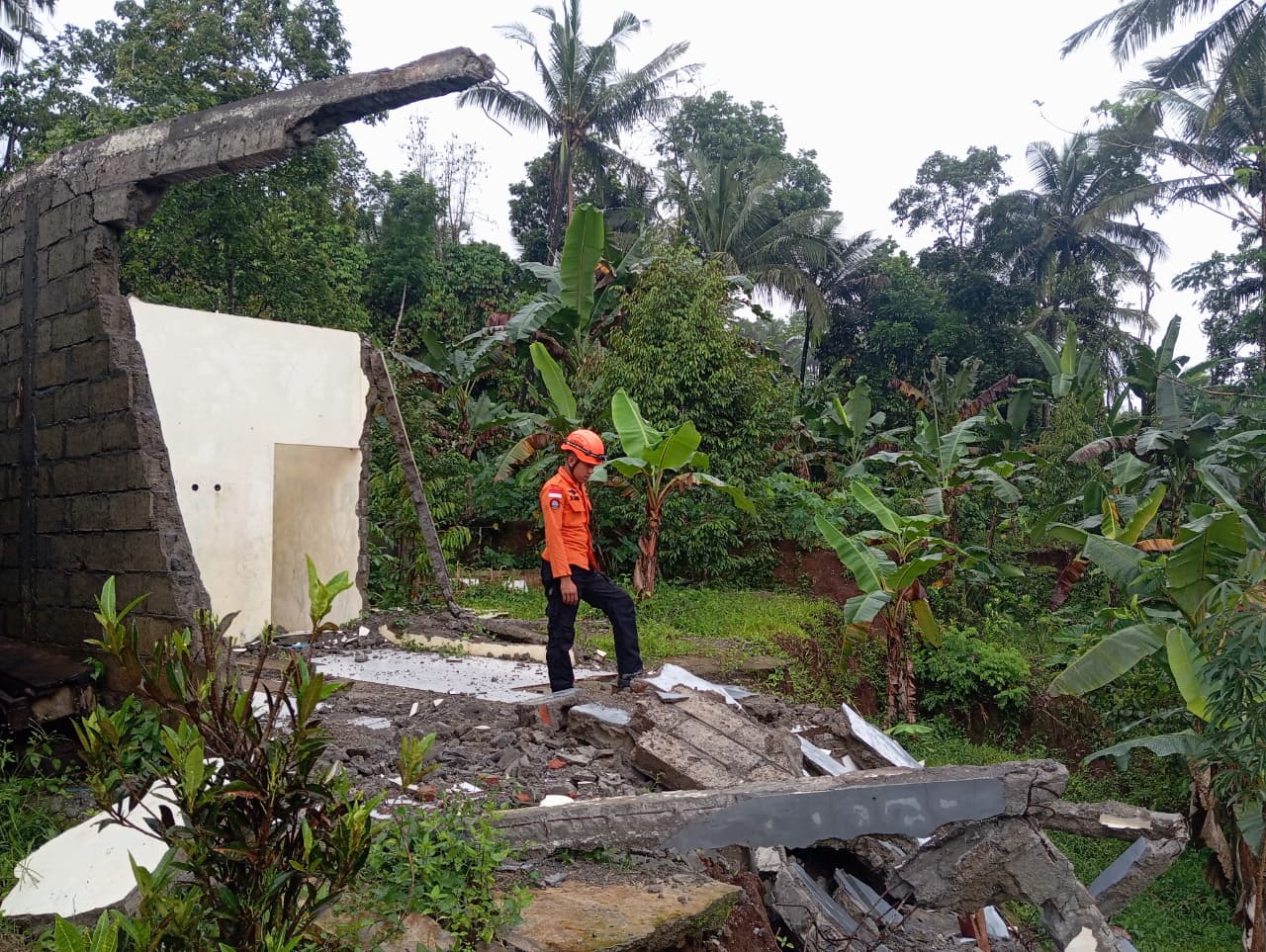 Petugas meninjau lokasi tanah bergerak yang membuat jalan ambles dan rumah retak di Kecamatan Kaliwiro.