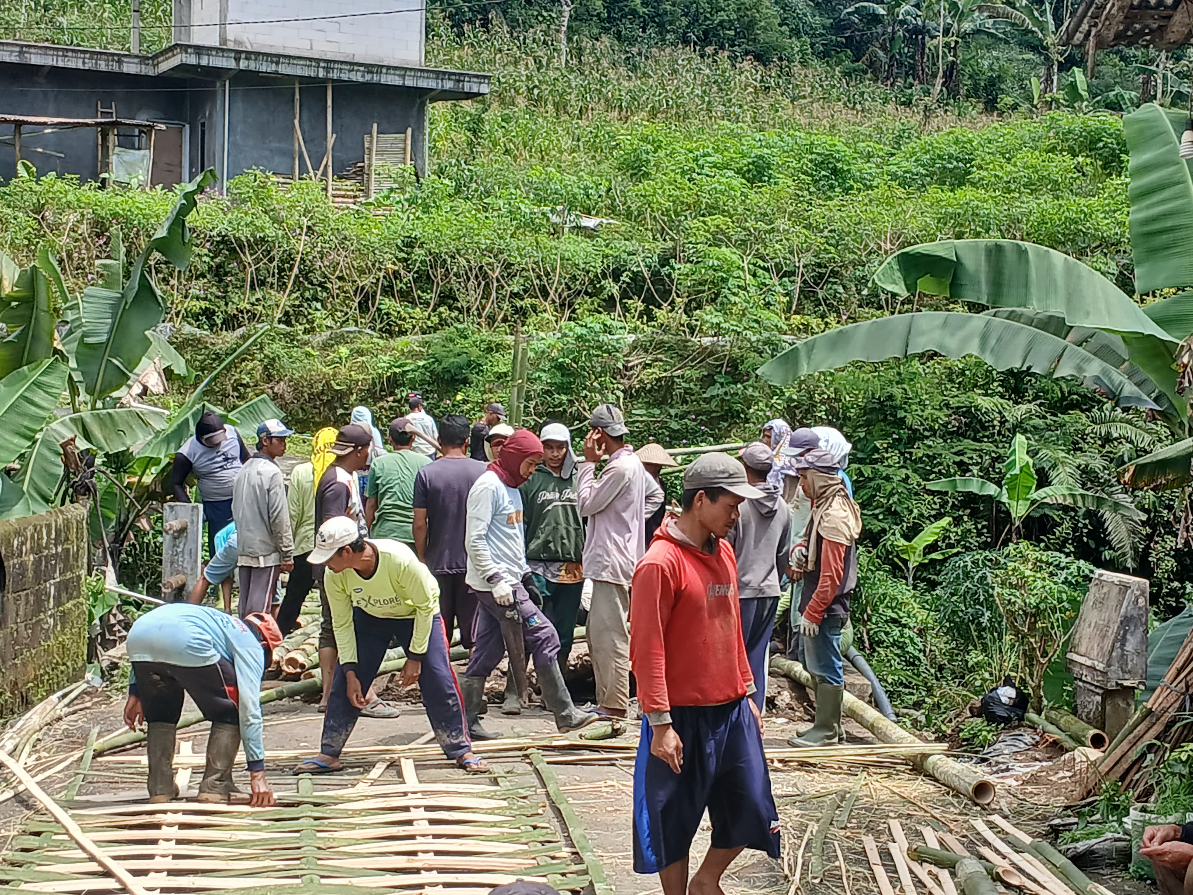 Warga gotong royong membuat jembatan darurat dari bambu agar bisa dilewati masyarakat.