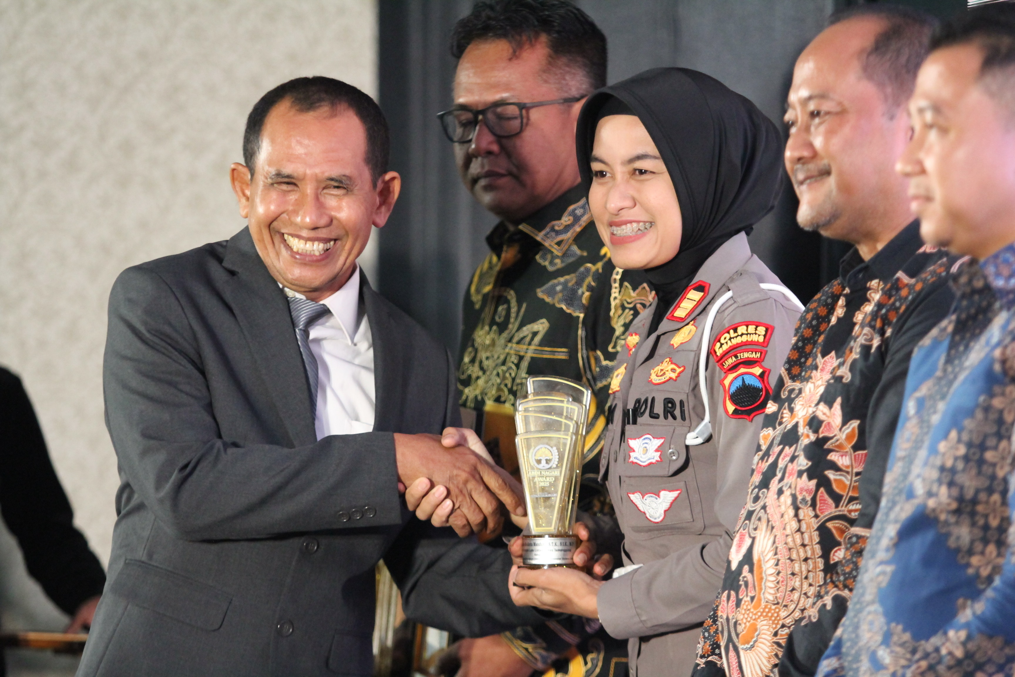Direktur Jawa Pos Radar Semarang Baehaqi menyerahkan piala kepada Kasatlantas Polres Temanggung AKP Yosra Meidicta Mandung di malam Anugerah Abdi Nagari di Hotel Noorman Semarang, Jumat (12/12/2025).
