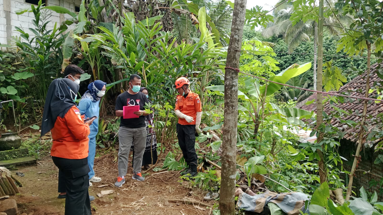 Petugas hendak mengevakuasi Mbah Sopirin yang ditemukan tewas di belakang rumahnya.