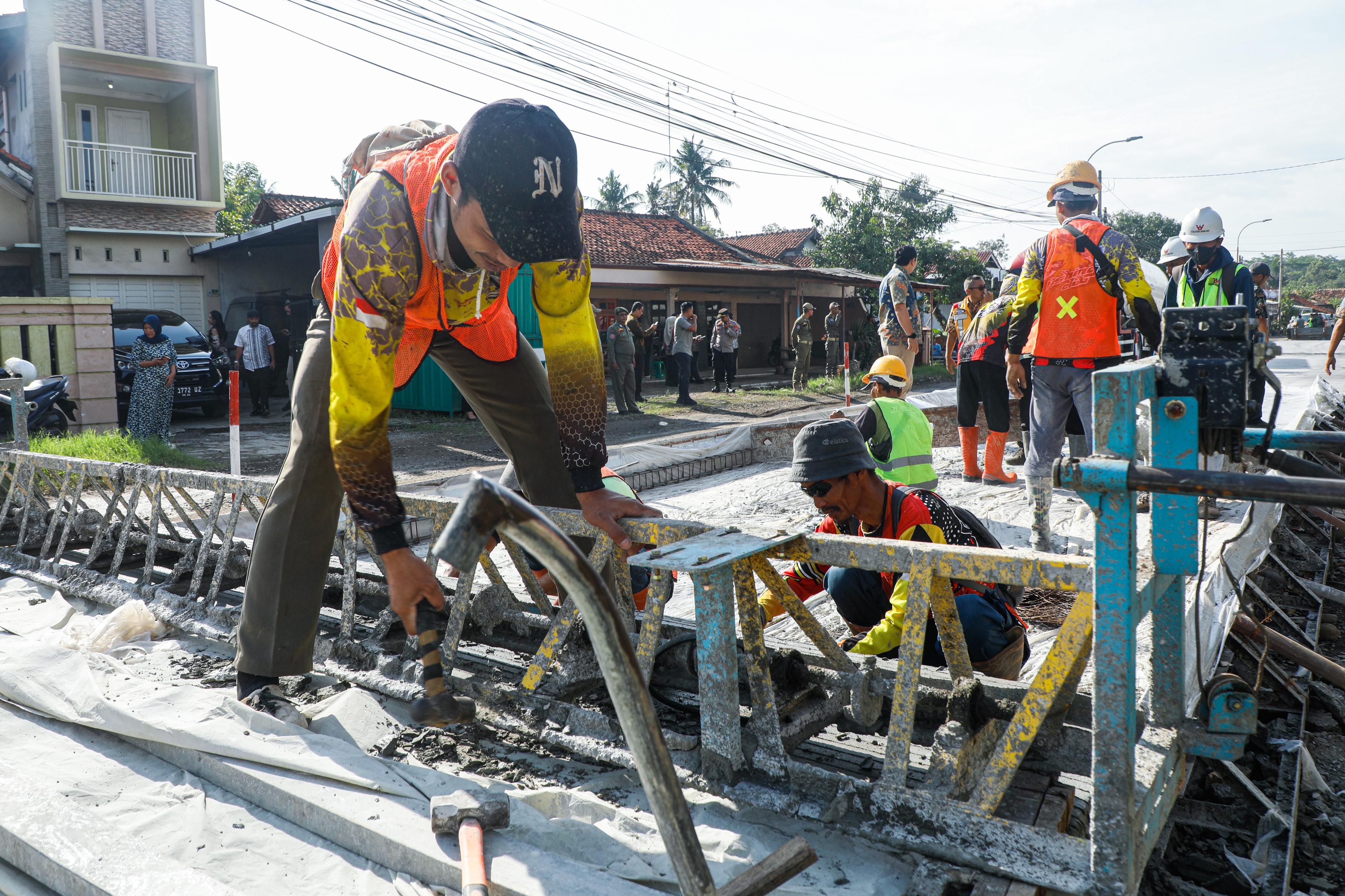 Pekerja sedang memperbaiki jalan rusak di wilayah Jawa Tengah.