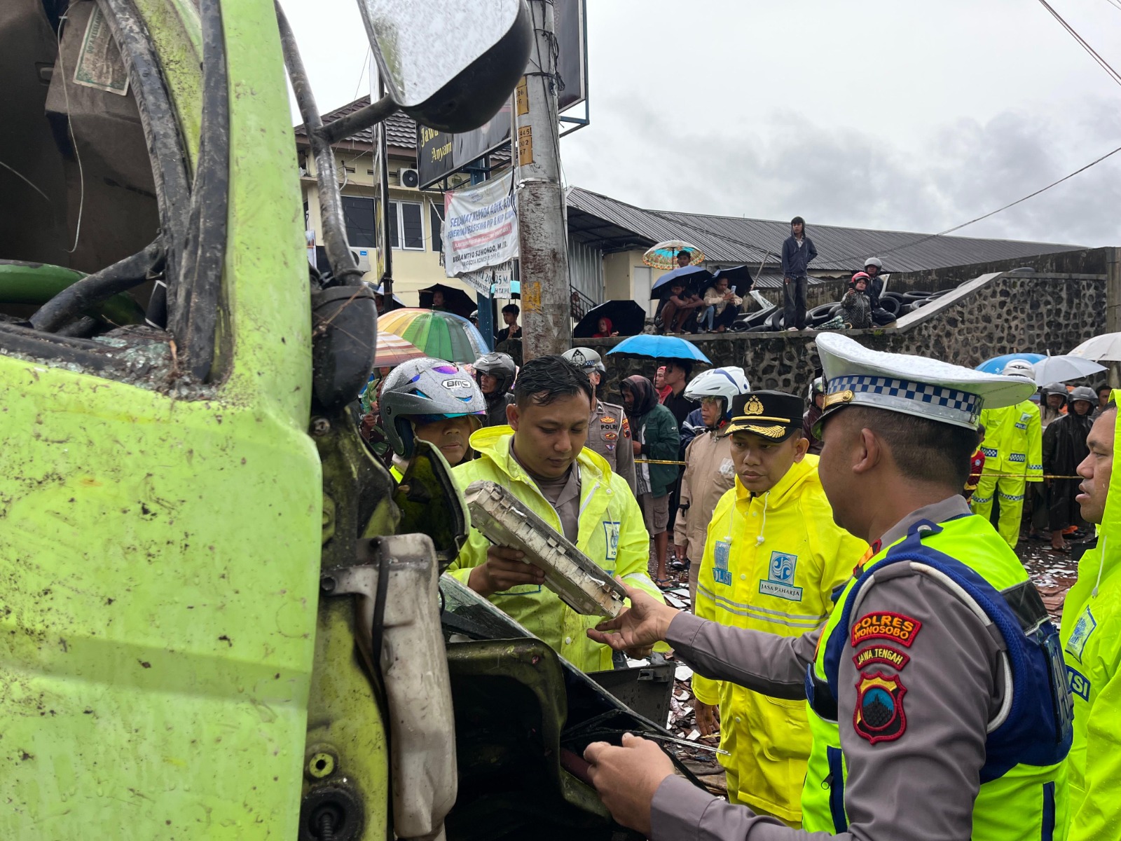Polisi saat melakukan penanganan pada truk tronton yang ringsek setelah menabrak sejumlah sepeda motor dan tugu di perempan Kertek Wonosobo, Sabtu (27/12/2025).