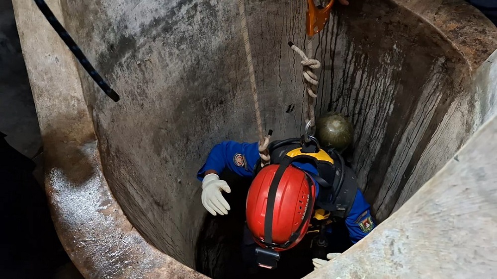 Salah satu anggota turun ke dalam sumur dilengkapi alat pernapasan Self-Contained Breathing Apparatus.