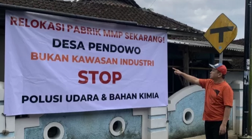 Warga Desa Pendowo, Kranggan menunjukkan spanduk protes terhadap operasional pabrik MMP yang diduga mencemari lingkungan.