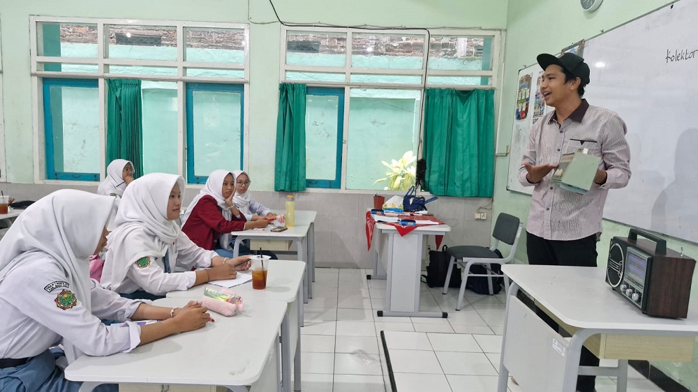 Dimas Indra Febriyanto mengenalkan koleksi radio transistor kepada pelajar.