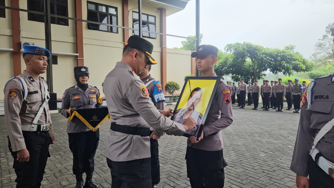 : Kapolres Temanggung AKBP Zamrul Aini mencoret foto anggota sebagai tanda diberhentikan dengan tidak hormat pada upacara secara in absentia di halaman Mapolres, Jumat (27/2/2026).  