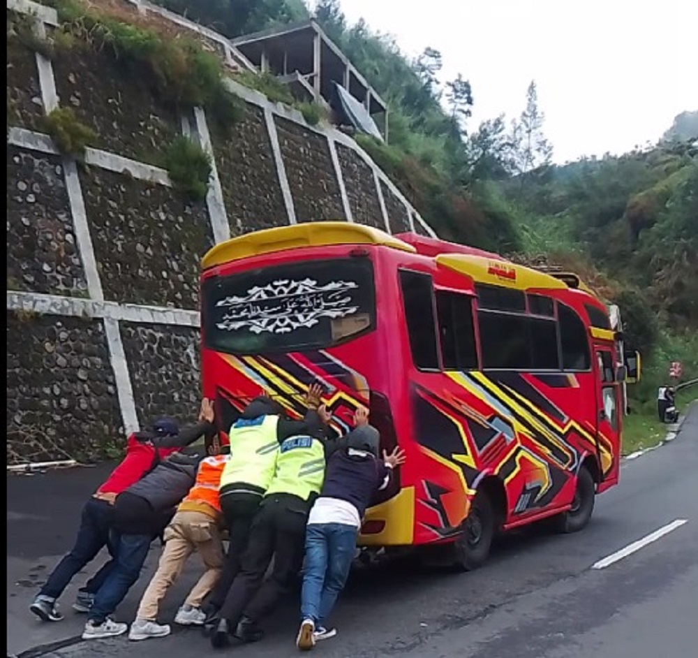  Petugas dibantu warga mendorong bus yang mogok di tanjakan ekstrem kawasan wisata Dieng, Kabupaten Wonosobo.  