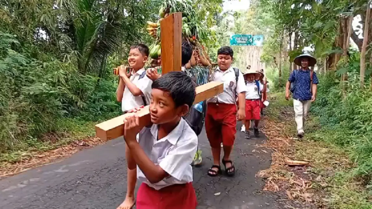 Salah satu siswa SD Kanisius Kenalan menopang salib dalam&nbsp;prosesi Jalan Salib menyusuri perbukitan Menoreh, Borobudur, Kabupaten Magelang, Senin (30/3). (ROFIK SYARIF/ JAWAPOS RADAR MAGELANG)