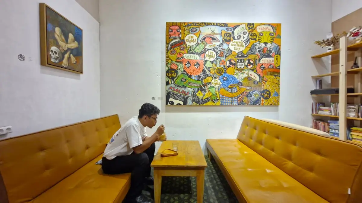 Pengunjung menikmati segelas kopi di bawah karya Gindring Wasted (2015) yang menghiasi dinding Call Me Coffee Roaster Intimate Bar, Rabu (3/6/2026). (PUPUT PUSPITASARI/JAWA POS RADAR MAGELANG)