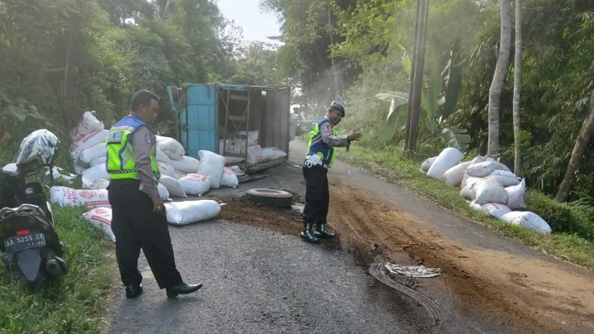 Dua petugas mengatur arus lalu lintas di lokasi truk pengangkut pupuk terguling di Kajoran, Kabupaten Magelang.