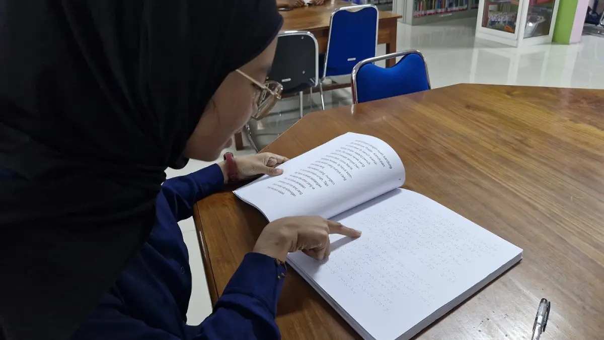 Seorang pengunjung Perpustakaan Umum Kota Magelang membuka buku braille yang tersedia di perpustakaan, Jumat (21/8/2026). (PUPUT PUSPITASARI/JAWA POS RADAR MAGELANG)