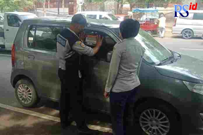 Petugas Dishub Kota Semarang, menempeli stiker pada kendaraan taksi online yang parkir sembarangan. (Istimewa)