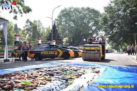 Ratusan botol minuman keras hasil operasi Polres Wonosobo dilindas menggunakan stoom, Senin (17/4/2023). (Sigit Rahmanto/Radar Magelang)