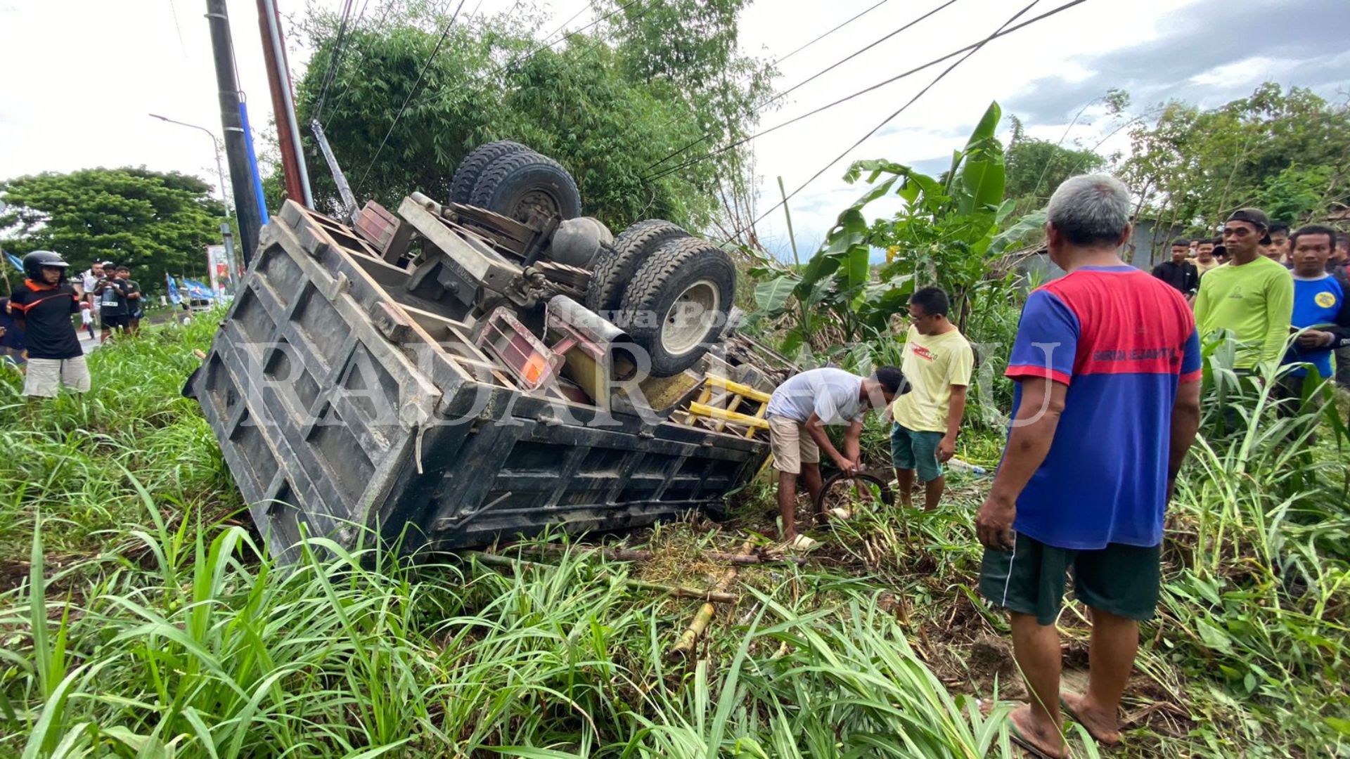RINGSEK: Kendaraan truk terbalik di parit setelah terlibat laka maut dengan sepeda motor di Jalan Raya Madiun-Ponorogo, Desa Slambur, Geger, Kabupaten Madiun, Jumat (19/1). (DIAN RAHAYU/RADAR LAWU)
