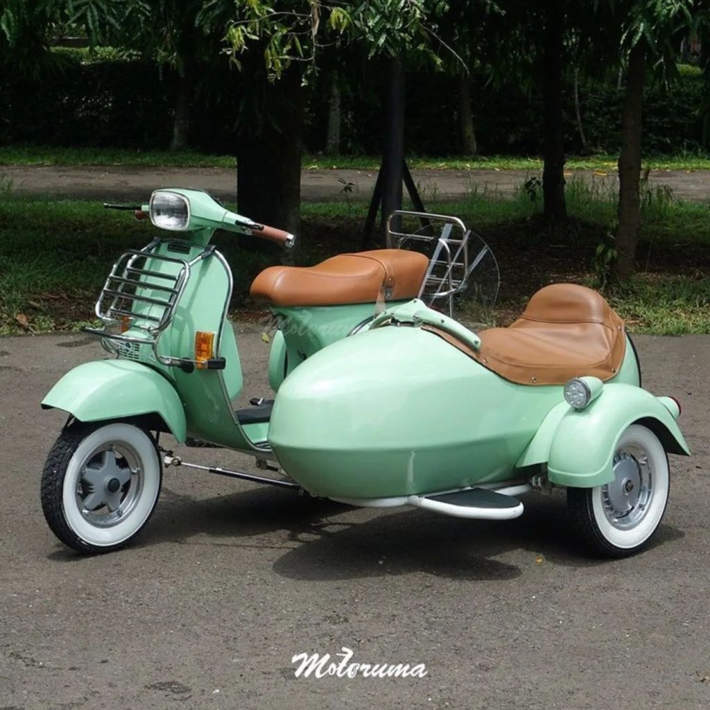 Vespa klasik dengan sespan custom tampil mencolok di jalan kota, simbol perpaduan sejarah, fungsi, dan gaya&nbsp;berkendara.