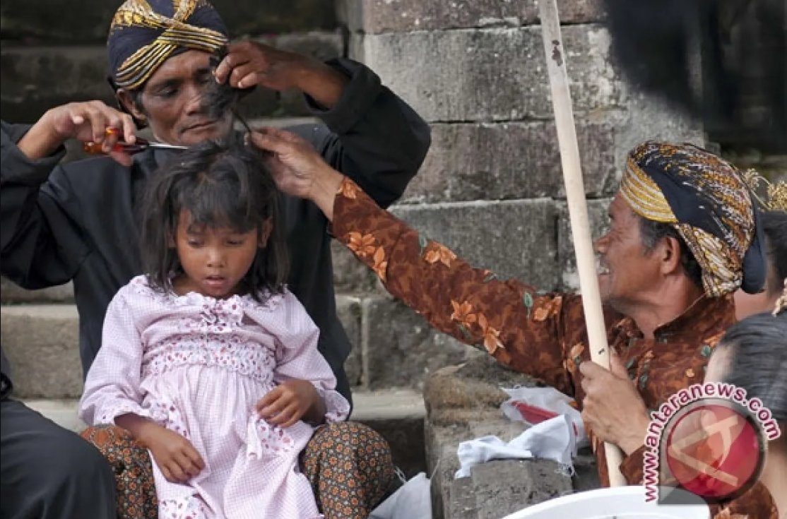 Pemangku adat memotong rambut anak gimbal dalam ritual ruwatan di Candi Arjuna, Dieng, Banjarnegara, Jawa Tengah.