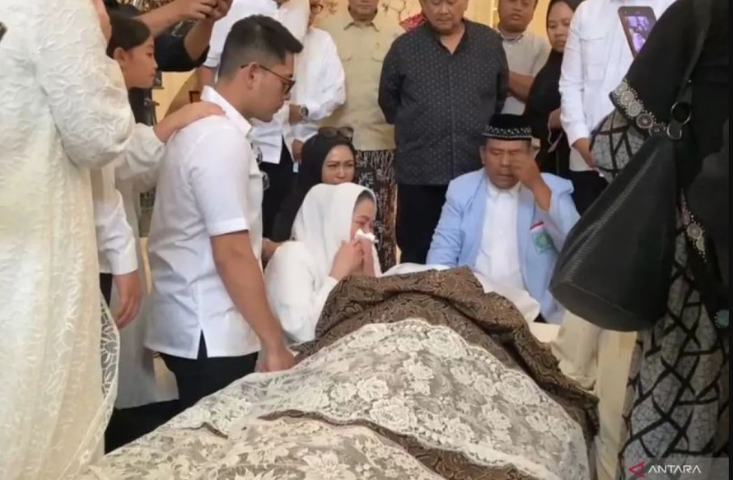 Wardhatul Asriah, tak kuasa membendung air mata saat duduk di samping jenazah suaminya tercinta yang disemayamkan di rumah duka, Jalan Cipinang Cempedak I No.30, Jatinegara, Jakarta Timur
