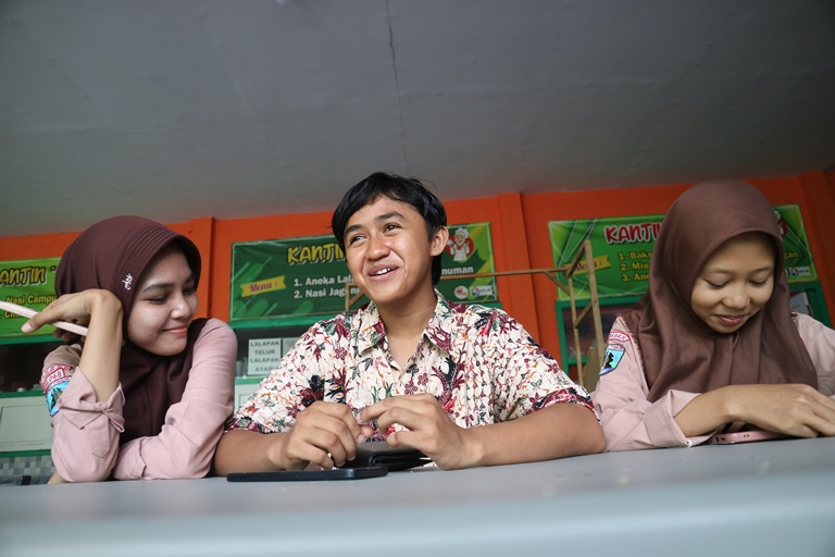 AKRAB: Vini Vidi Vici (tengah) bersama dua temannya berbincang di kantin SMKN 5 Jember. (DWI SISWANTO/RADAR JEMBER)  &nbsp;