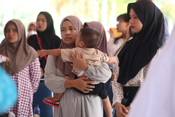 MOMONGAN: Salah seorang anak bersama ibunya ketika mengikuti penerimaan bantuan PMT dari Pemkab Jember di Kelurahan Mangli, kemarin (3/7). YULIO FA/RADAR JEMBER
