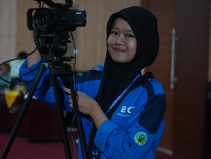 FOKUS: Siswa SMKN 1 Jember, Andini Triyas Saputri, mengoperasikan kamera live streaming di ruang Auditorium Universitas Jember. (YULIO FA/RADAR JEMBER)