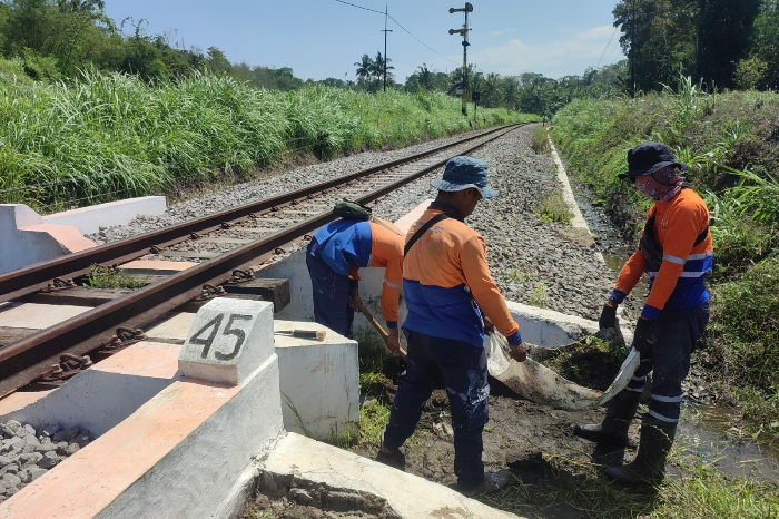 ANTISIPASI: Petugas membersihkan drainase yang melintasi jalur kereta api antara Stasiun Ledokombo&ndash;Stasiun Sempolan, kemarin (18/11). (KAI DAOP 9 JEMBER)
