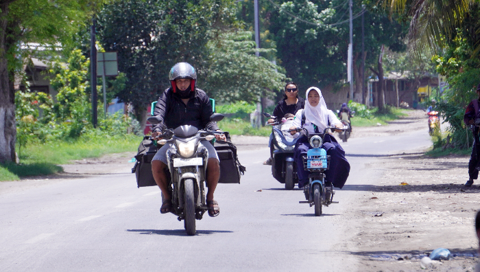 SAMA-SAMA TAK PAKAI HELM: Pelajar di Puger menggunakan sepeda listrik dan melintas di jalan raya. YULIO FA/RADAR JEMBER