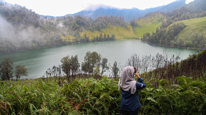 MENIKMATI: Petugas Taman Nasional Bromo Tengger Semeru (TNBTS) mengabadikan pesona Ranu Kumbolo saat pertama kali dibuka, Senin (23/12). MUHAMMAD HASBI/RADAR SEMERU