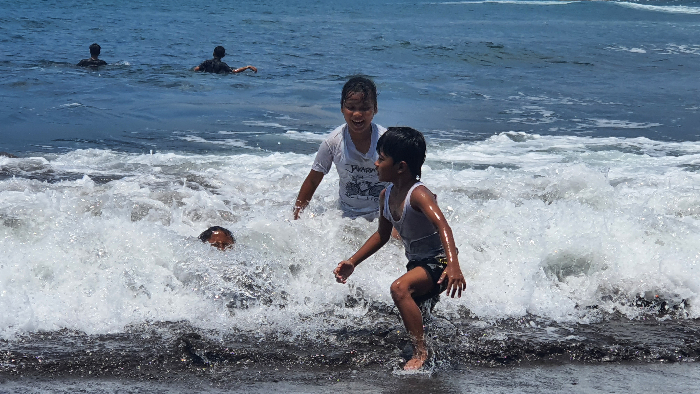 BAHAYA: Anak-anak asik mandi di Pantai Payangan. Dari kejauhan terlihat remaja yang menantang ganasnya ombak laut selatan, Rabu (29/1). AZZQAL AZQIYA