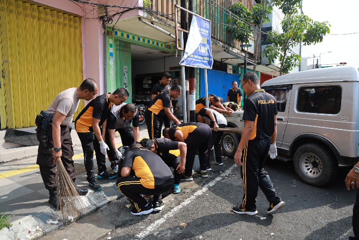 KERJA BAKTI: Polisi bersama sejumlah elemen masyarakat membersihkan sampah di sekitar Jalan Sultan Agung Jember. POLRES