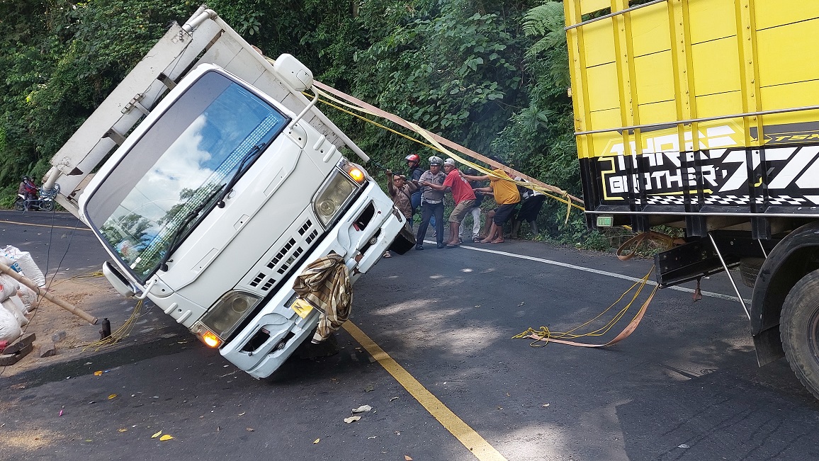 TERGULING: Evakuasi truk bermuatan kotoran ayam di Jalur Gumitir, Desa Sidomulyo, Kecamatan Silo, Jember, Selasa (29/4/2025). (Foto: Jumai/Radar Jember)