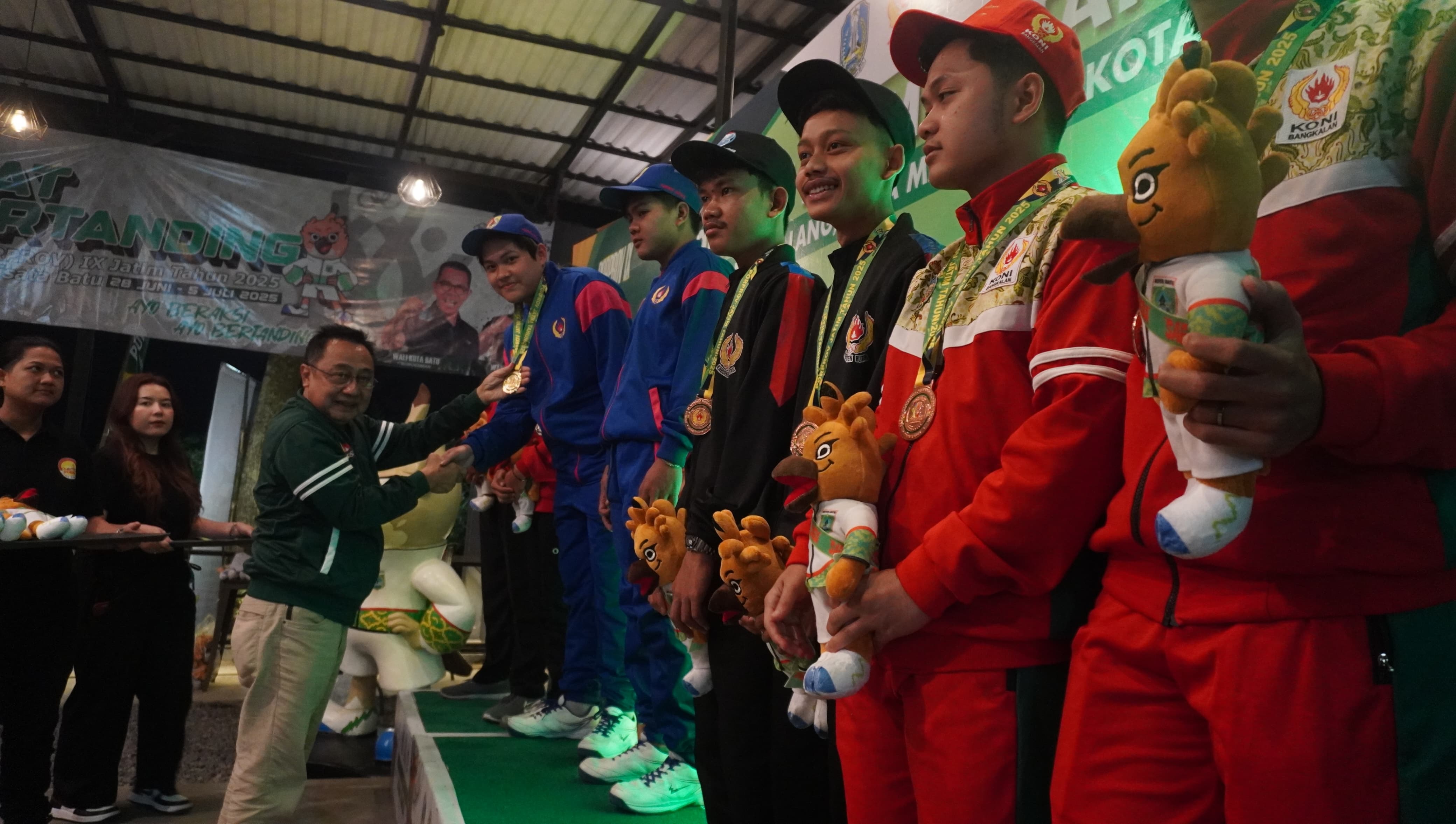 Ketua KONI Jember Sutikno memberikan medali emas ke atlet biliar Jember Edrick Danu Wijaya dan Trading Juwarenda, kemarin malam (1/7) di Carabao Pool, Kota Batu.