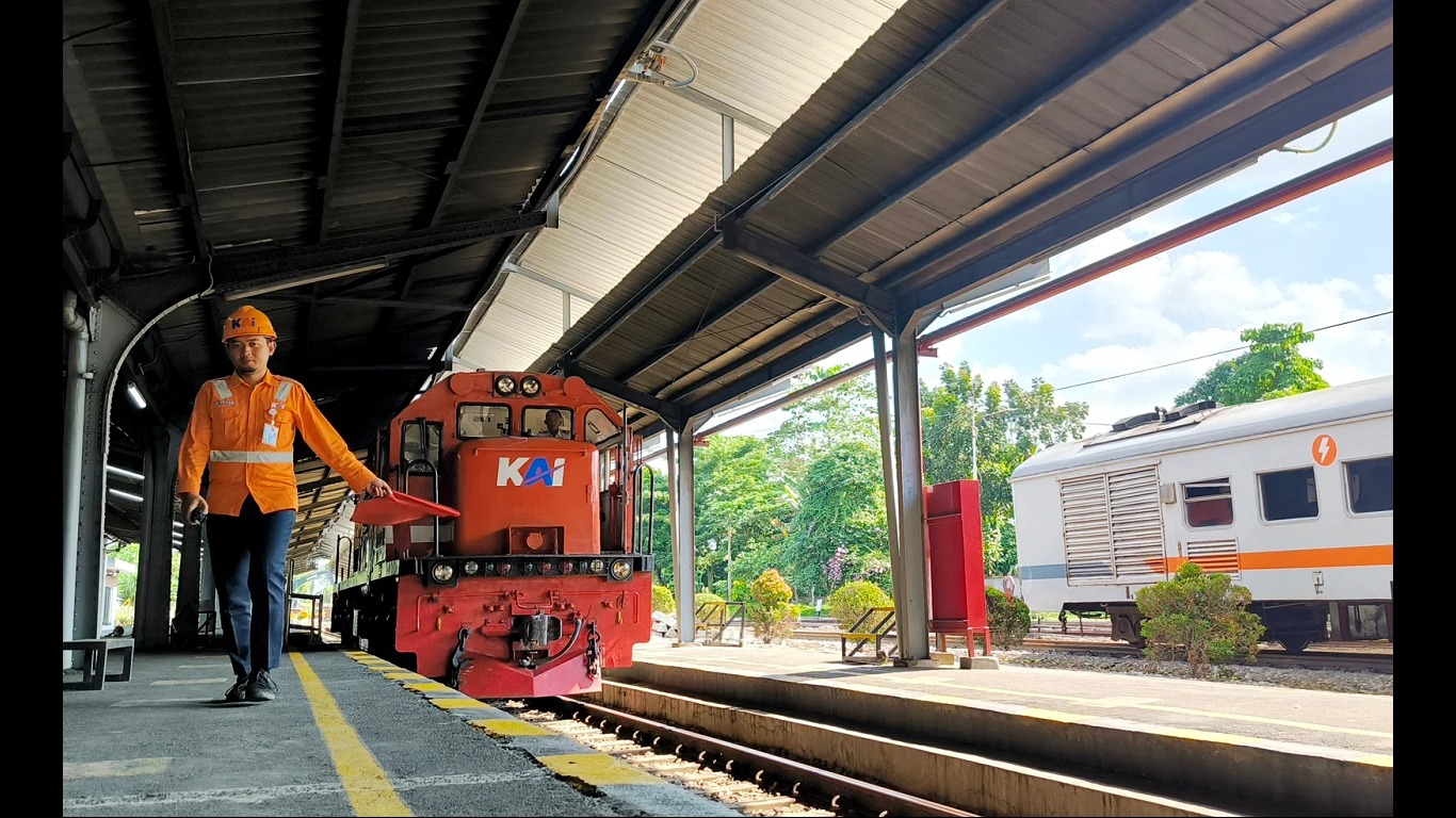 MENGARAHKAN: Petugas langsir (PLR) memandu masinis merangkaikan lokomotif ke jalur rangkaian kereta api di Stasiun Jember. (MEGA SILVIA/RADAR JEMBER)