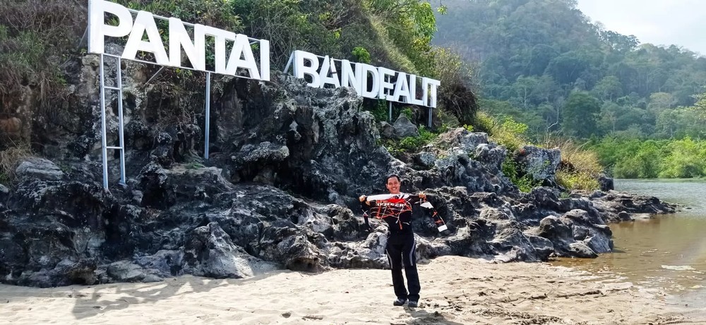 A visitor poses in front of the Pantai Bandealit sign, a quiet and beautiful beach in Jember. Photo: Radar Jember