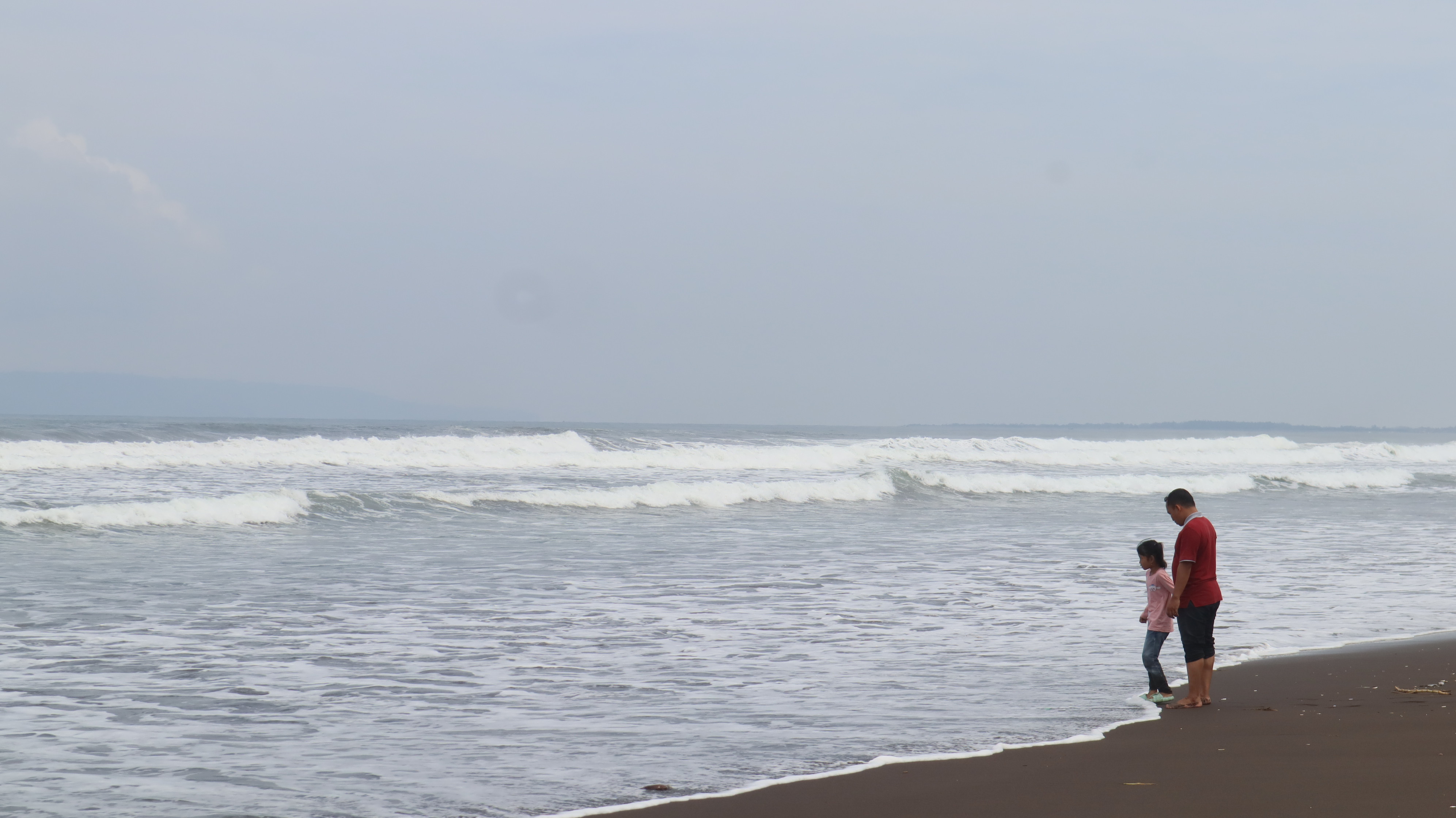 A father and daughter enjoy the gentle waves at Pancer Puger Beach in Jember, on April 11. Photo: Delia Enggar Sugiana