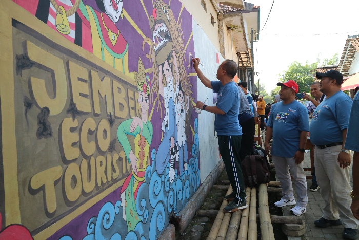 MAKIN CANTIK: Kacabdin Jember Sugeng Trianto secara simbolis menggoreskan cat pada gambar mural di Gang Ara samping SMAN Arjasa, kemarin (9/8).