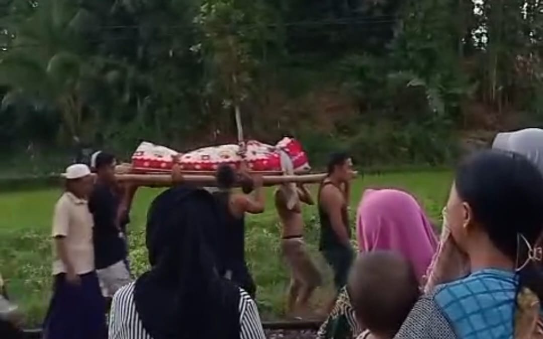 Warga mengevakuasi jenazah seorang ibu yang tertemper KA Pandanwangi di Ledokombo, Jember.