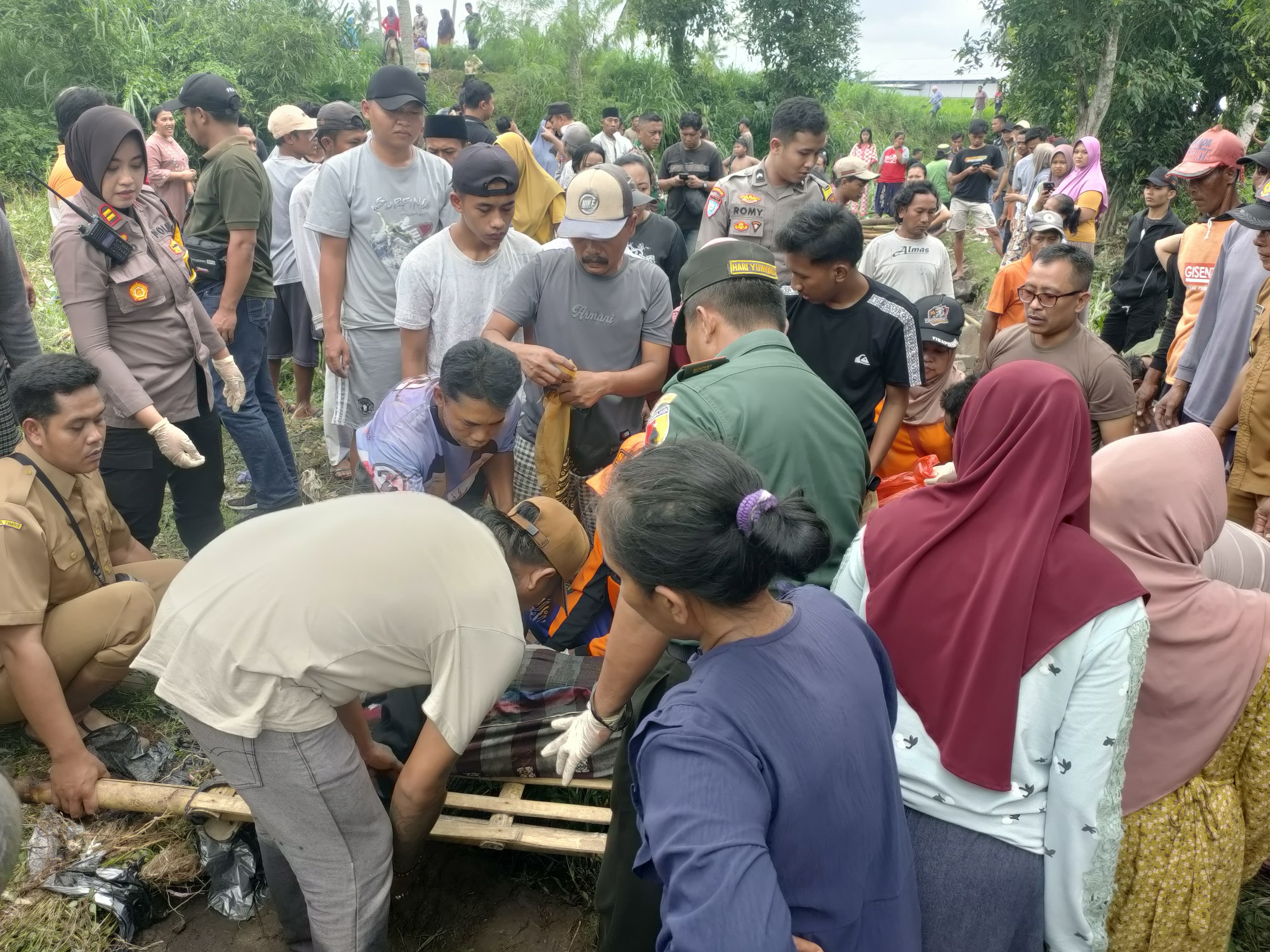 Warga mengevakuasi jenazah lansia di Kalisat Jember. Diduga korban terseret banjir saat bencana terjadi kemarin.