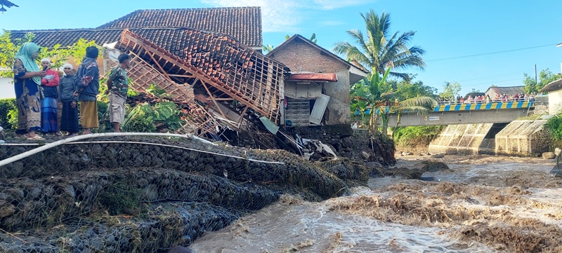 BERBAHAYA: Banjir bandang melanda, dua rumah warga di pinggir sungai rusak. (JUMAI/RADAR JEMBER)