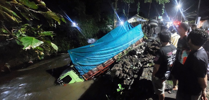 NYEBUR SUNGAI: Truk gandeng kelelep nyebur sungai akibat blong, di Jalan Wolter Monginsidi, Jember. (JUMAI/RADAR JEMBER)